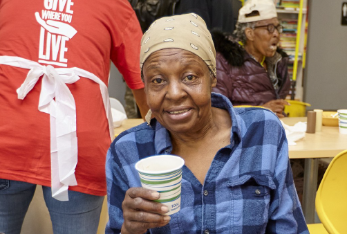 A woman looks at the camera as she holds a cup in her hand